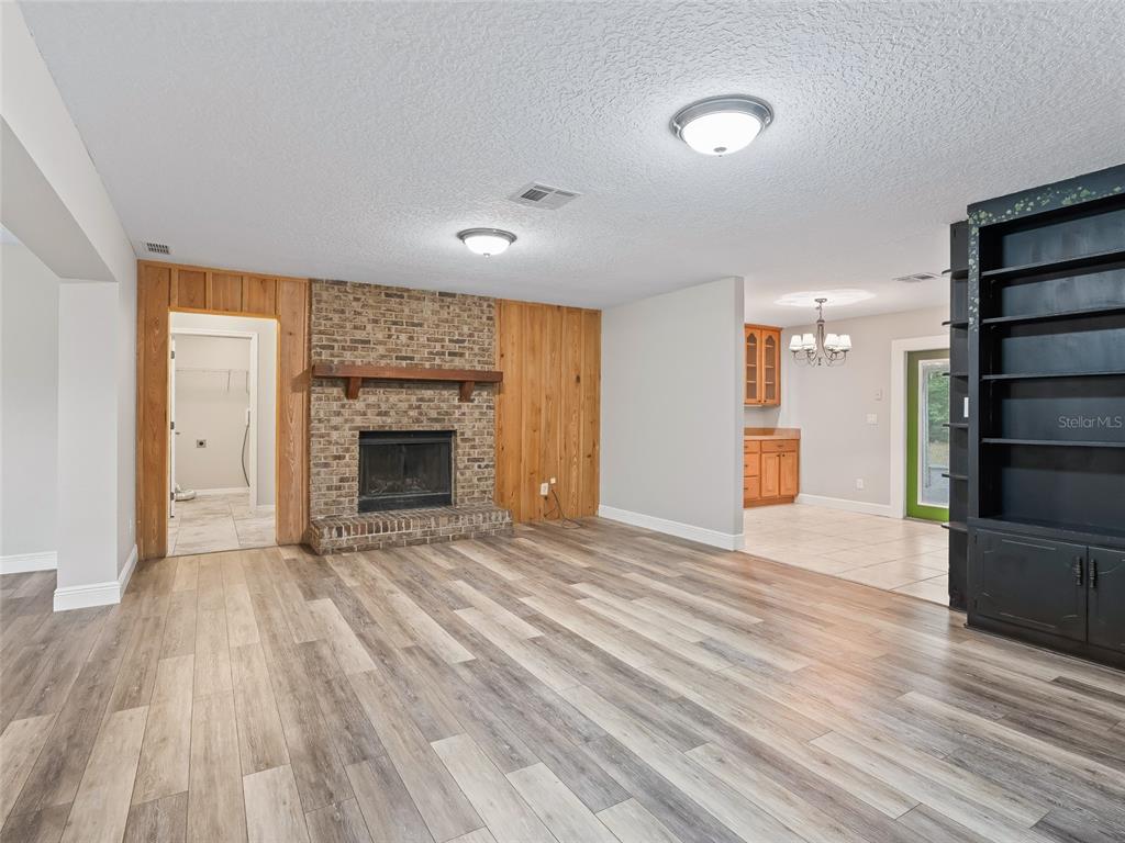 8234 Highway 301 Bushnell, FL 33513 - Photo 7 of 52 an empty room with wooden floor fireplace and windows