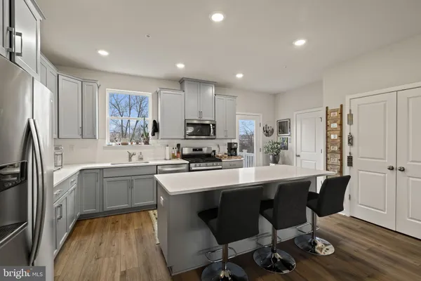 a kitchen with stainless steel appliances granite countertop a sink a stove a refrigerator cabinets and a dining table with wooden floor