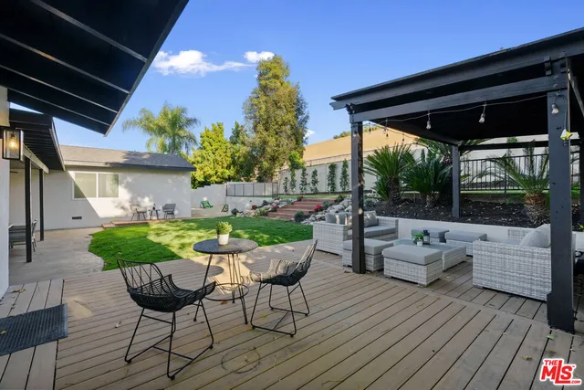 a view of a patio with table and chairs potted plants with wooden floor and fence