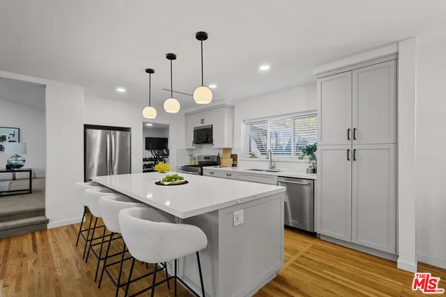 a kitchen with stainless steel appliances kitchen island granite countertop a stove a sink a dining table and chairs with wooden floor