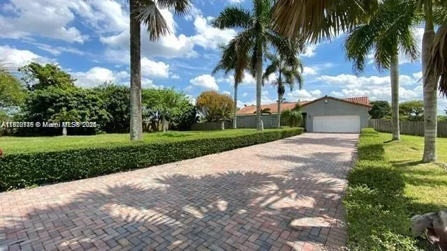 a view of a white house with a big yard and palm trees