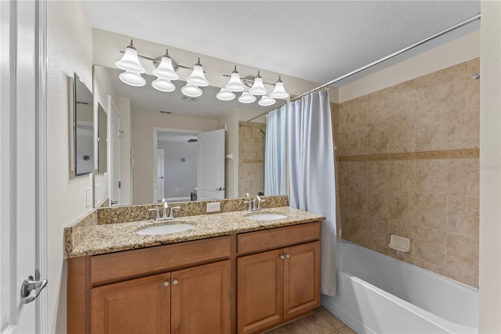 8955 Bismarck Palm Road Kissimmee, FL 34747 - Photo 25 of 32 a bathroom with a granite countertop sink a large mirror and a bathtub