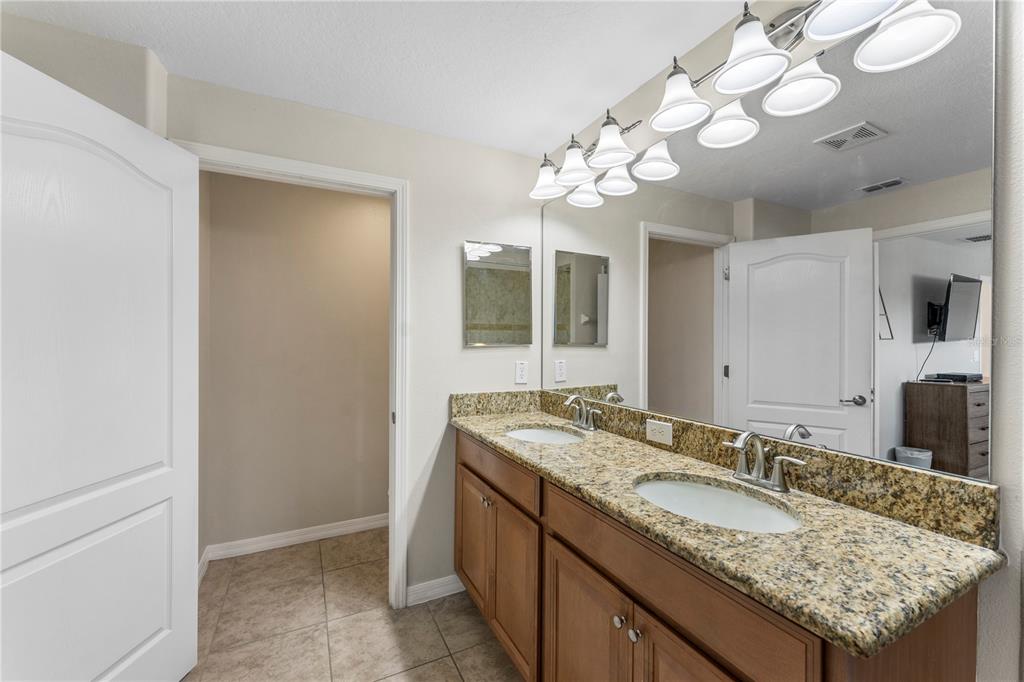 8955 Bismarck Palm Road Kissimmee, FL 34747 - Photo 26 of 32 a bathroom with a granite countertop double vanity and a mirror