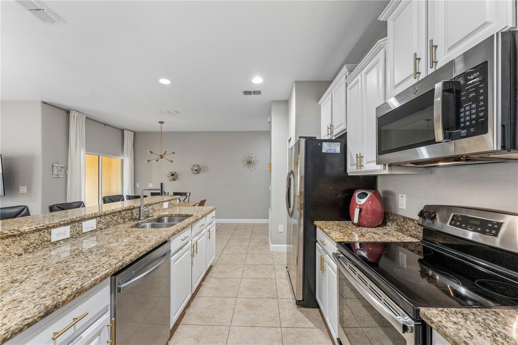 8955 Bismarck Palm Road Kissimmee, FL 34747 - Photo 7 of 32 a kitchen with stainless steel appliances granite countertop a sink and a stove