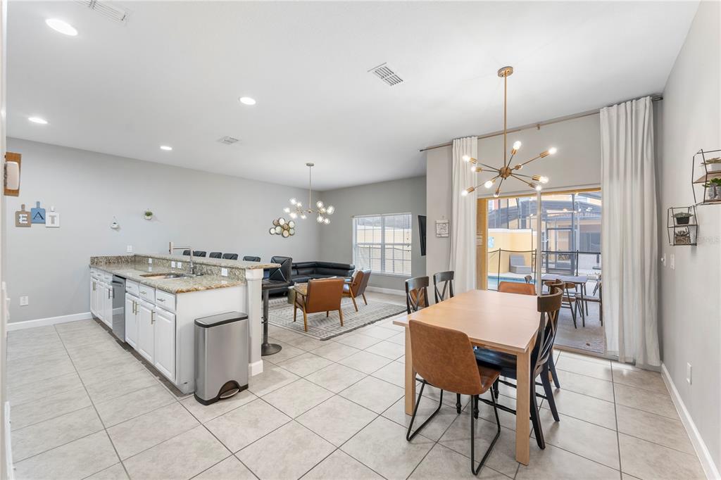 8955 Bismarck Palm Road Kissimmee, FL 34747 - Photo 9 of 32 a open kitchen with stainless steel appliances granite countertop a stove top oven a sink dishwasher with a dining table and chairs