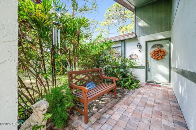 a bench sitting in backside of a house with potted plants