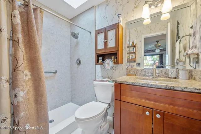 a bathroom with a granite countertop sink toilet and shower