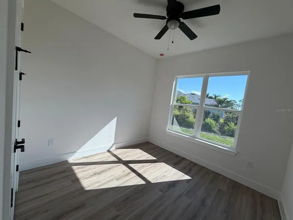 a view of an empty room with wooden floor and a window