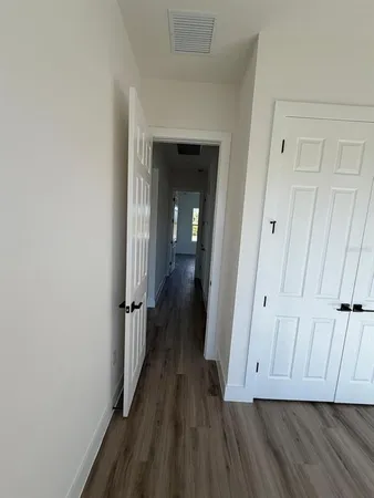 a view of a hallway with wooden floor and closet