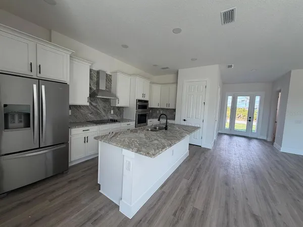 a kitchen with stainless steel appliances granite countertop a refrigerator a sink dishwasher a stove and white countertops with wooden floor