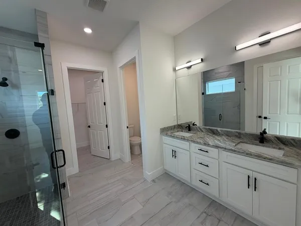 a bathroom with a granite countertop sink a mirror and a shower