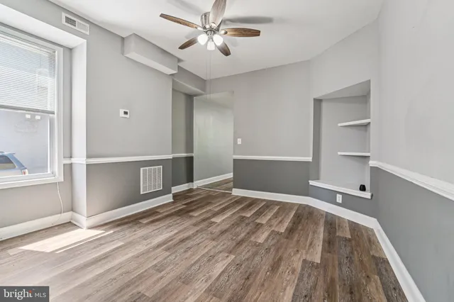 a view of empty room with wooden floor and fan