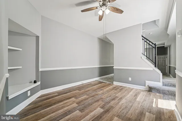 a view of an empty room with wooden floor and a chandelier