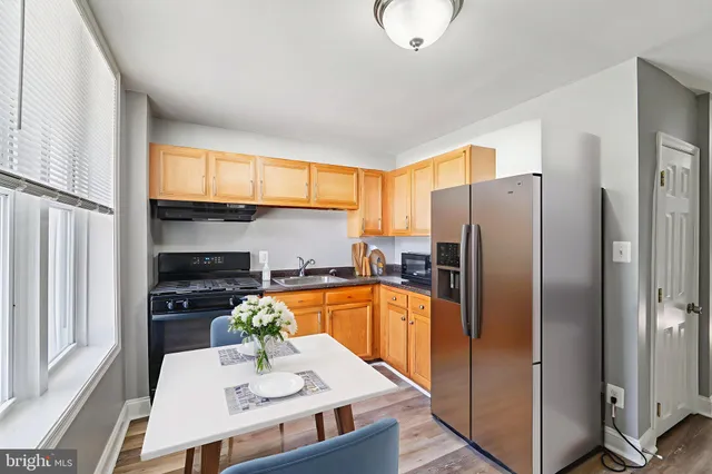 a kitchen with stainless steel appliances a refrigerator a stove a sink cabinets and a dining table