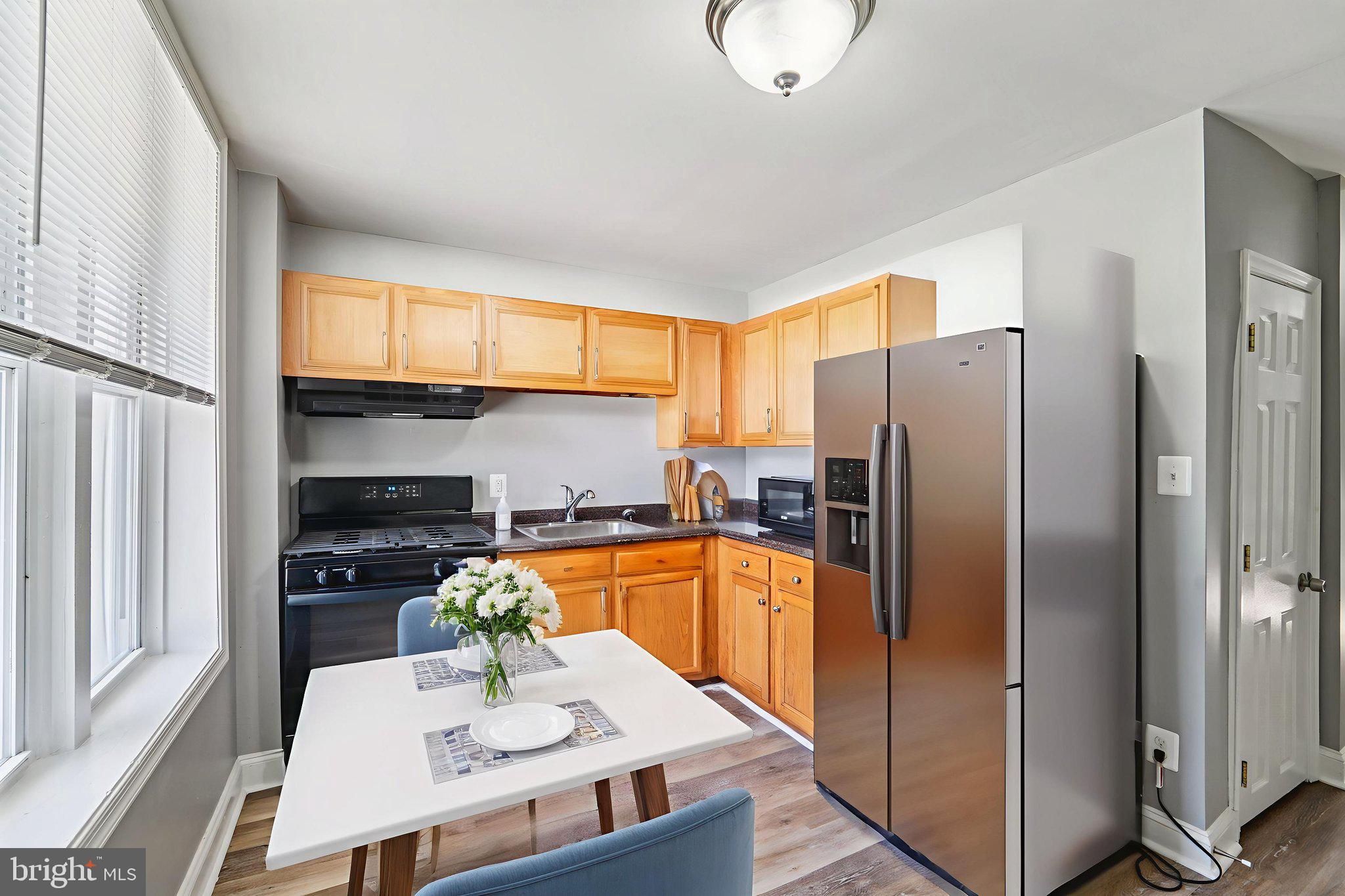 1820 East Lafayette Avenue Baltimore, MD 21213 - Photo 8 of 17 a kitchen with stainless steel appliances a refrigerator a stove a sink cabinets and a dining table
