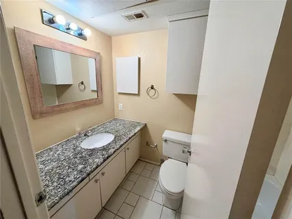 a bathroom with a granite countertop sink mirror vanity and toilet