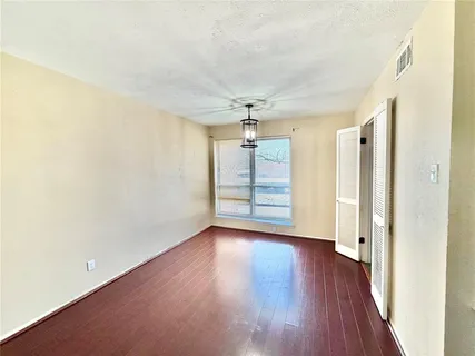 an empty room with wooden floor closet and windows