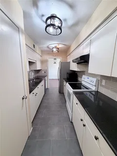 a large kitchen with cabinets stove top oven and sink