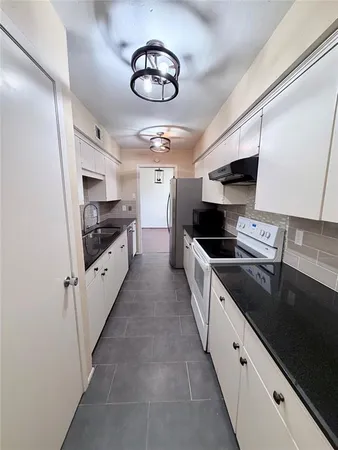 a large kitchen with cabinets stove top oven and sink
