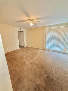 an empty room with windows & ceiling fan view