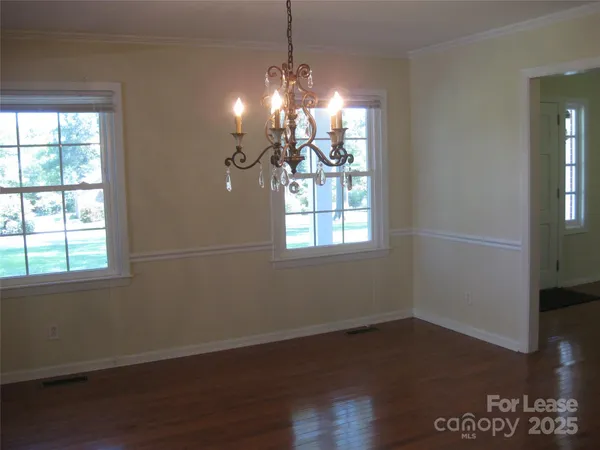 a room with wooden floor chandelier and windows