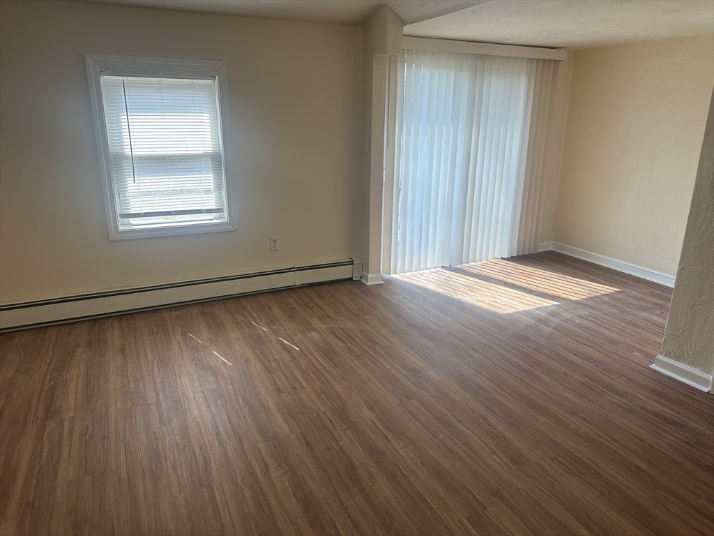 56 Howe Avenue, Unit 1 Shrewsbury, MA 01545 - Photo 6 of 10 an empty room with wooden floor and windows