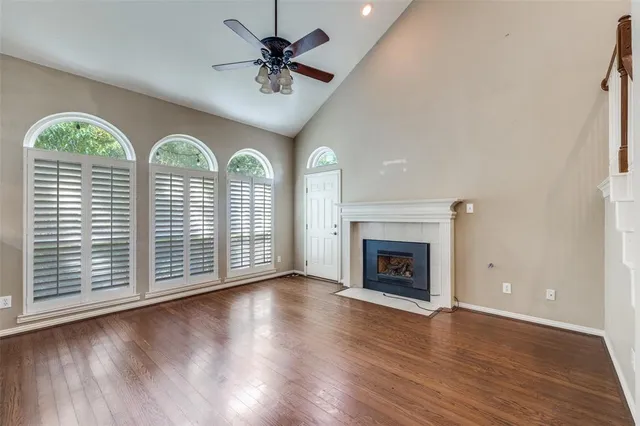 an empty room with wooden floor fan and windows