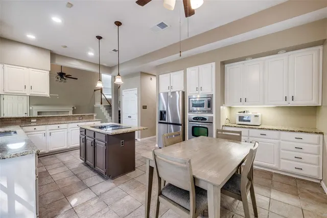a kitchen with stainless steel appliances kitchen island granite countertop a table chairs sink and cabinets