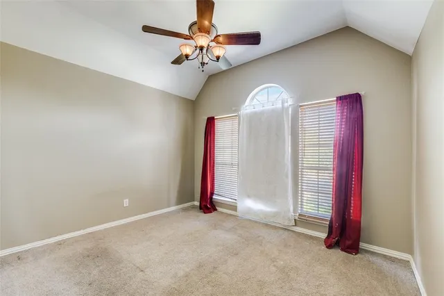 an empty room with a chandelier fan and windows