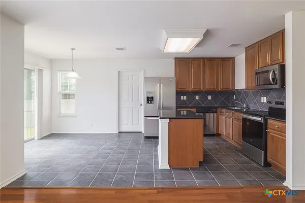 a kitchen with granite countertop a refrigerator and a stove top oven