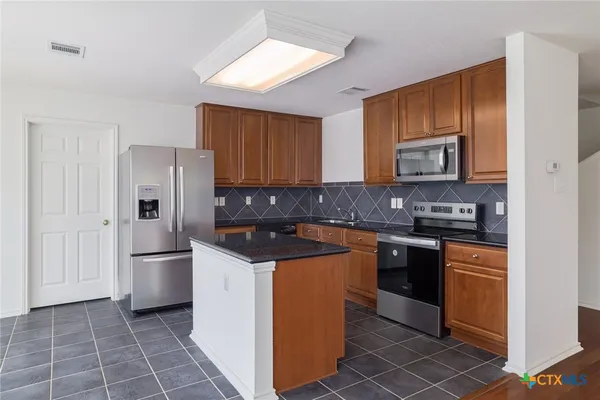a kitchen with stainless steel appliances granite countertop a refrigerator stove and sink