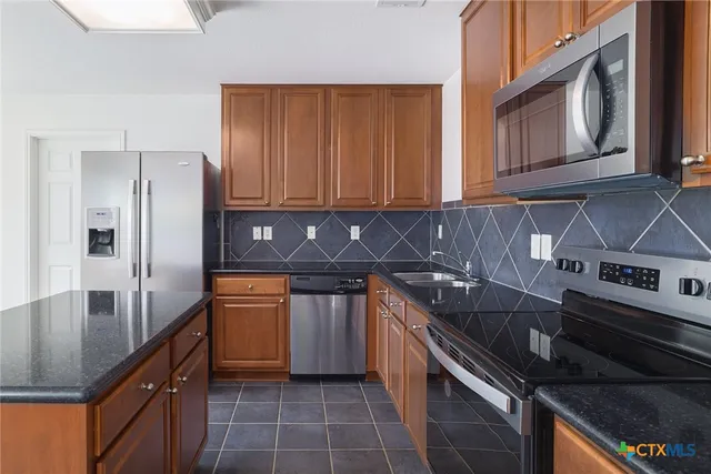 a kitchen with stainless steel appliances granite countertop a sink stove and refrigerator