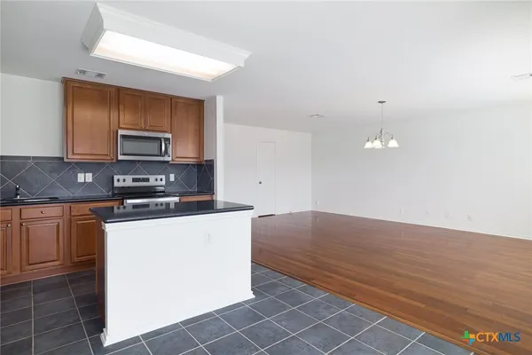 a kitchen with stainless steel appliances granite countertop a stove a sink and a microwave