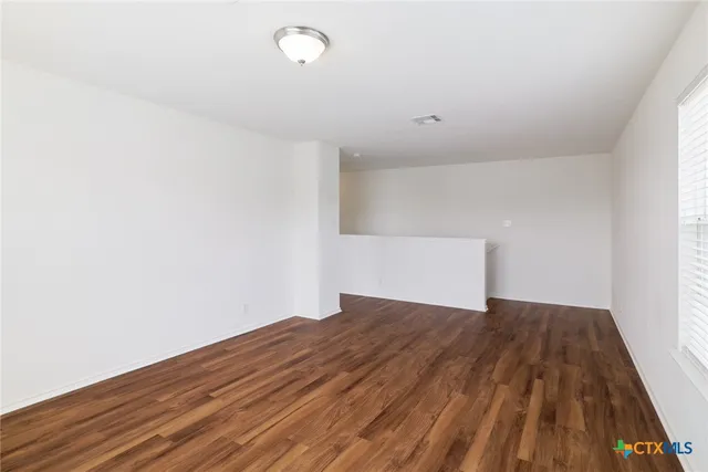 a view of a big room with wooden floor and windows