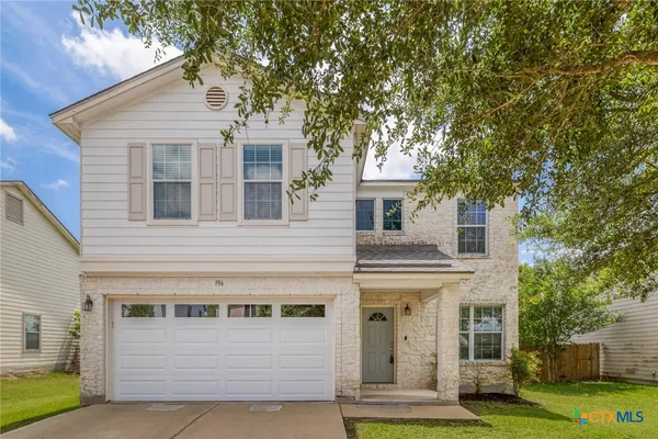 a front view of a house with a yard garage and wooden fence