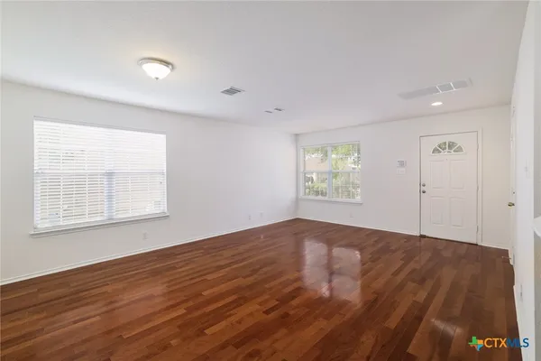 an empty room with wooden floor and windows