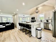 275 Sound Road Greenport, NY 11944 - Photo 28 of 28 Kitchen featuring light countertops, a kitchen bar, light wood-type flooring, open floor plan, and vaulted ceiling