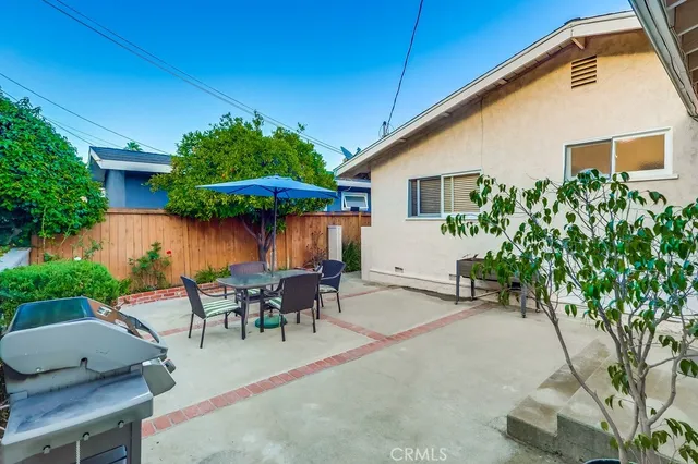 a backyard of a house with table and chairs under an umbrella