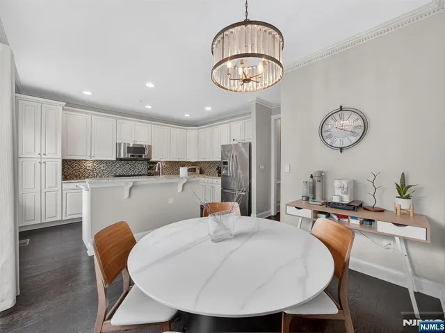 a kitchen with stainless steel appliances granite countertop a dining table chairs a refrigerator a sink a stove a dining table and chairs