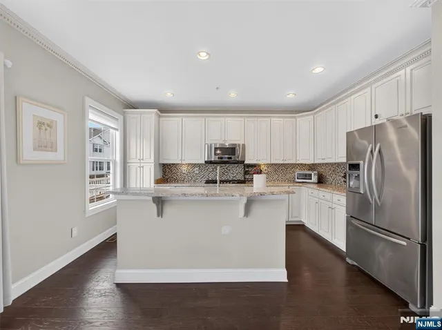 a kitchen with stainless steel appliances white cabinets and a refrigerator
