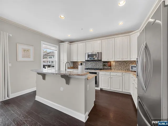 a kitchen with granite countertop white cabinets and stainless steel appliances