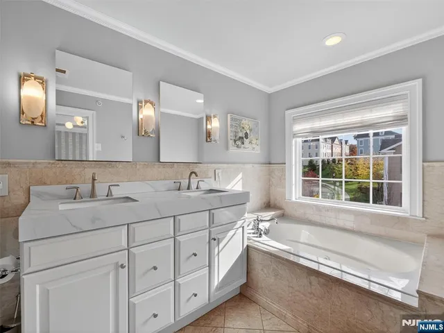a bathroom with a sink double vanity mirror and a bathtub