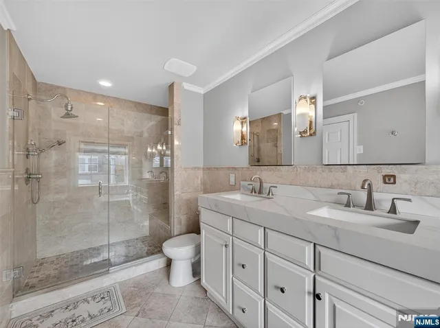 a bathroom with a double vanity sink toilet mirror and shower