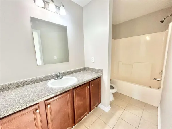 a bathroom with a granite countertop sink a toilet and bathtub