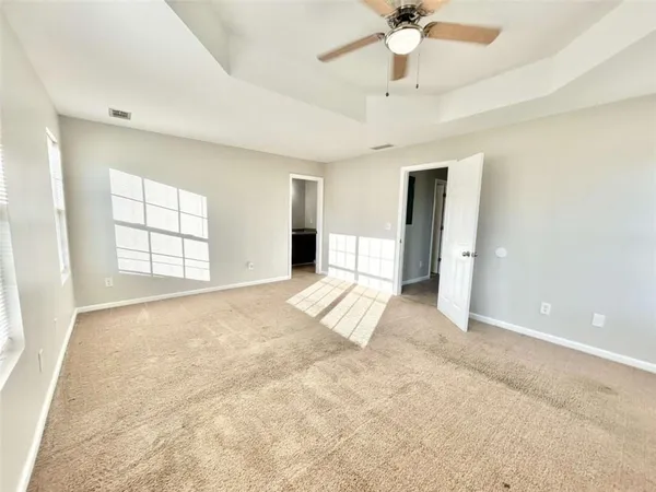 an empty room with windows and ceiling fan