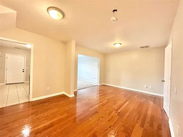 a view of an empty room with wooden floor and a window