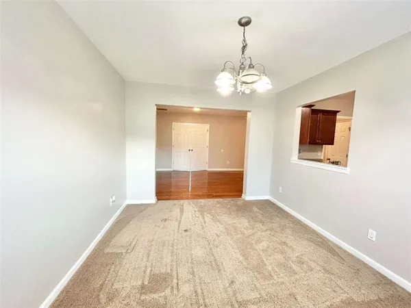 an empty room with wooden floor chandelier and windows