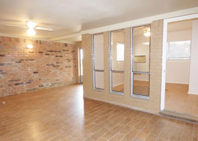 a view of an empty room with a window and wooden floor