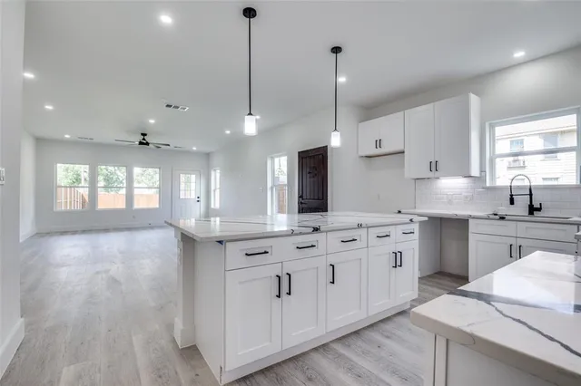 a kitchen with kitchen island granite countertop a sink a counter space appliances and a window