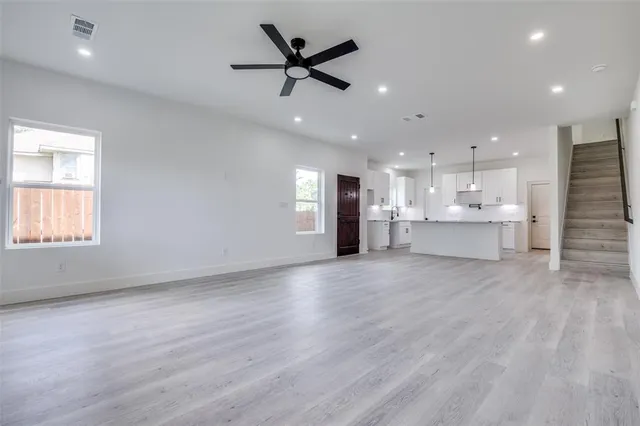 a view of an empty room with kitchen appliances and a ceiling fan